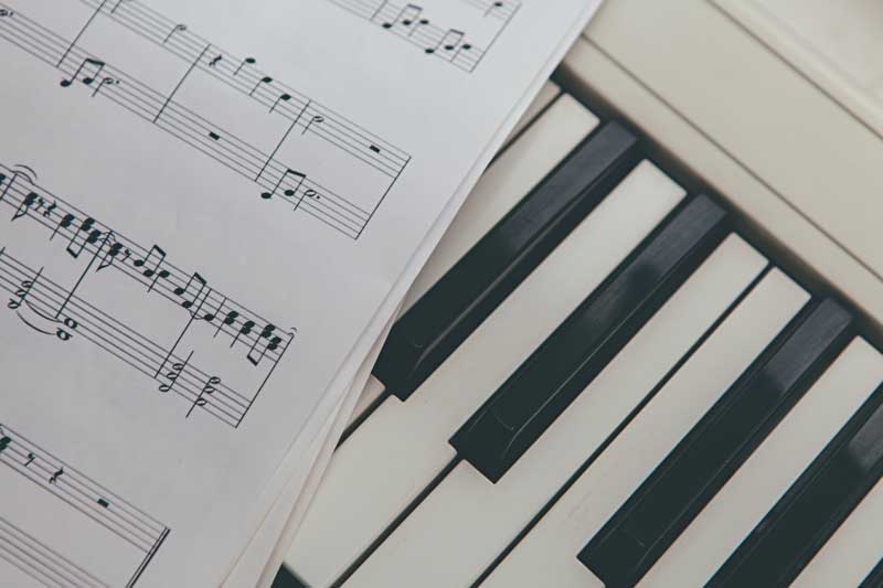 Das Bild zeigt eine Klaviertastatur mit Notenblatt